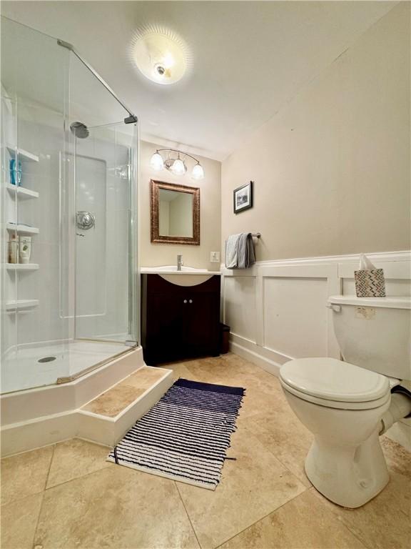 214 Fairfield Dr, Horseheads, NY 14845 - bathroom with a shower stall, toilet, vanity, a decorative wall, and tile patterned flooring