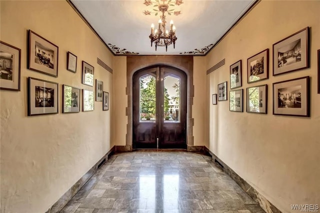 foyer featuring arched walkways, a chandelier, and french doors