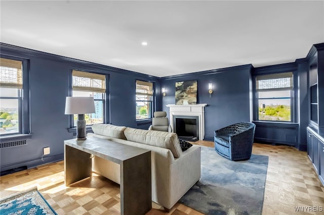 living area with crown molding, a glass covered fireplace, and recessed lighting