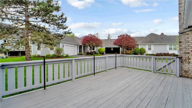 wooden deck featuring an attached garage and driveway