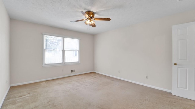 spare room featuring a ceiling fan, light carpet, and baseboards