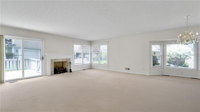 unfurnished living room featuring a chandelier, light carpet, a fireplace, baseboards, and a textured ceiling