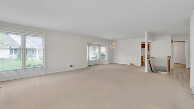 unfurnished room with a chandelier, light colored carpet, and baseboards