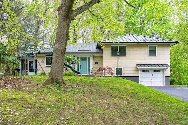 split level home featuring a standing seam roof, metal roof, asphalt driveway, and an attached garage