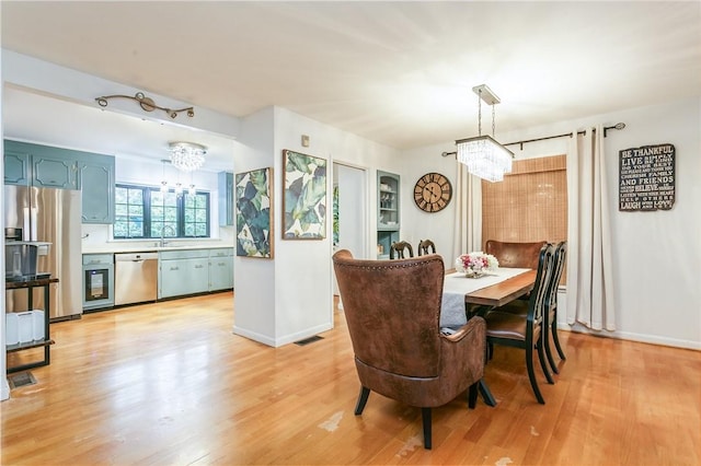dining room with a chandelier, light wood finished floors, and baseboards