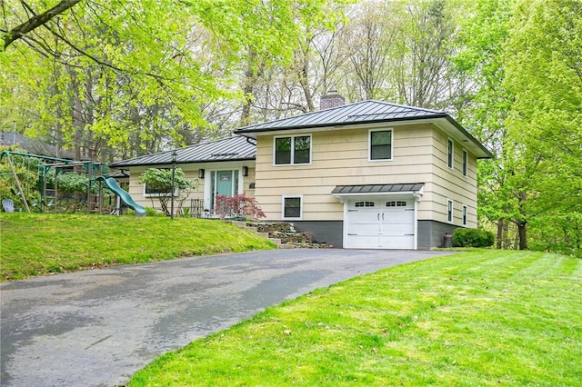 split level home with a standing seam roof, a chimney, metal roof, driveway, and an attached garage