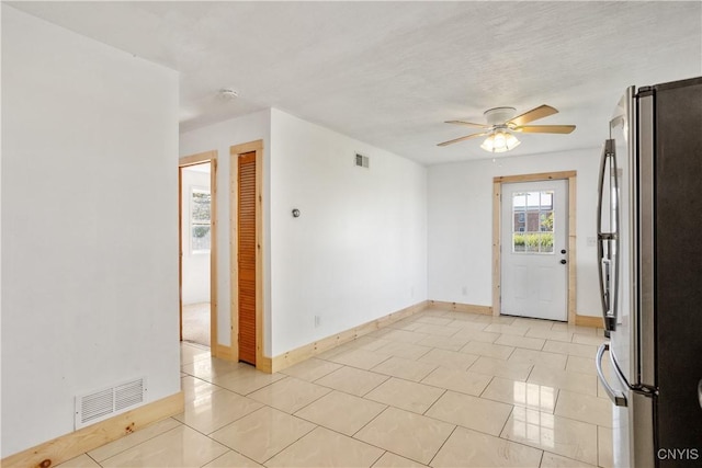 empty room featuring ceiling fan, baseboards, light tile patterned floors, and a smoke detector