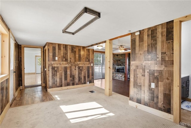 carpeted spare room featuring wooden walls and ceiling fan