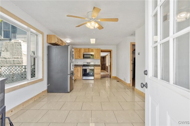 kitchen with appliances with stainless steel finishes, baseboards, a ceiling fan, light brown cabinets, and light tile patterned floors
