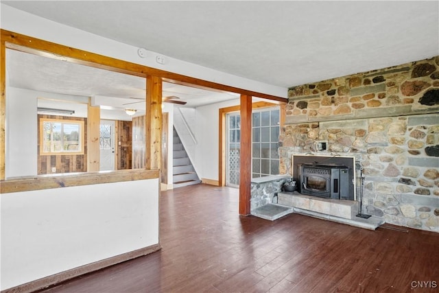 unfurnished living room featuring stairway, wood finished floors, and baseboards