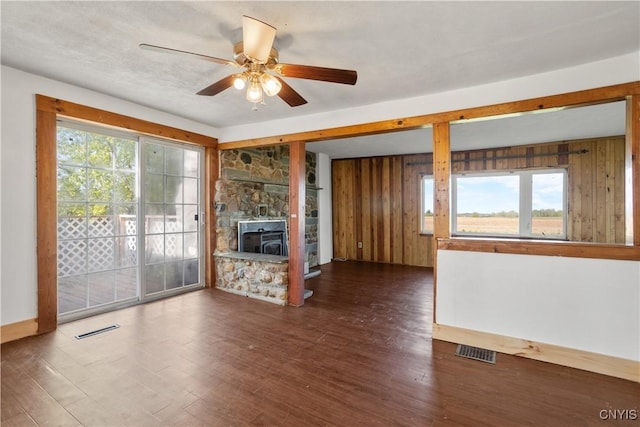 unfurnished living room with ceiling fan, healthy amount of natural light, wood finished floors, and wood walls