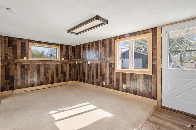 unfurnished room featuring wood walls, plenty of natural light, a smoke detector, and attic access