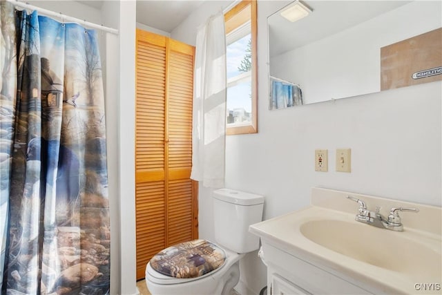 bathroom with vanity, toilet, and a closet