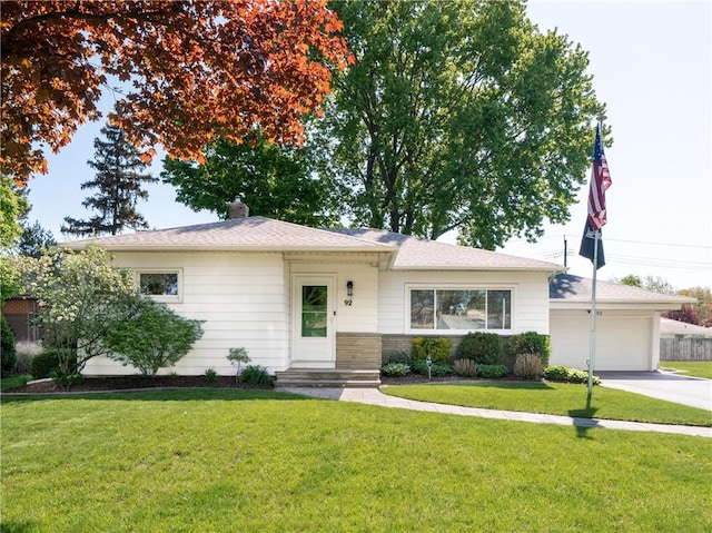 view of front of home featuring an attached garage, concrete driveway, a front lawn, and brick siding