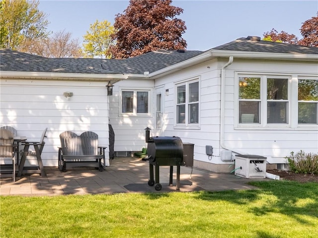 rear view of house featuring a patio area, a lawn, and roof with shingles