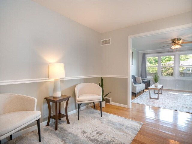 living area featuring wood finished floors, ceiling fan, and baseboards