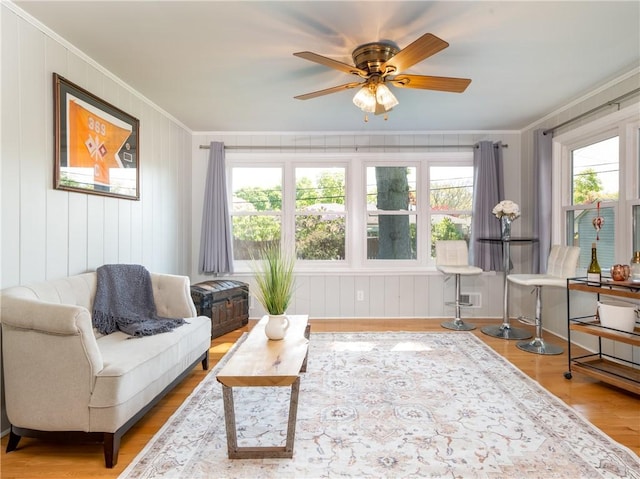 living area with crown molding, wood finished floors, and ceiling fan