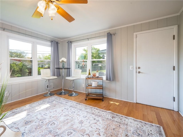 living area featuring crown molding, wood finished floors, and a ceiling fan