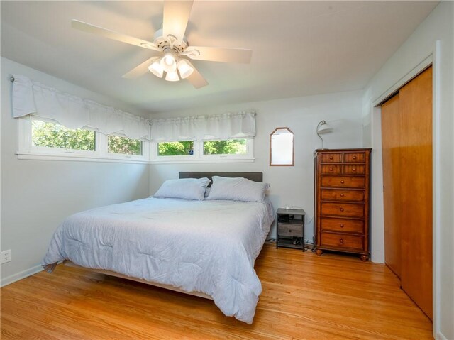 bedroom with multiple windows, light wood finished floors, a closet, and a ceiling fan