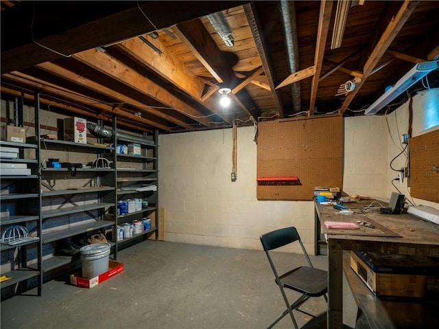 unfinished basement featuring concrete block wall and a workshop area