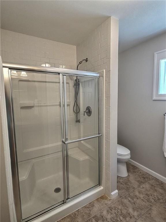 bathroom with a stall shower, toilet, baseboards, and tile patterned flooring
