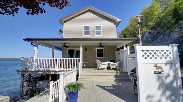 back of house with a ceiling fan, a deck with water view, and fence