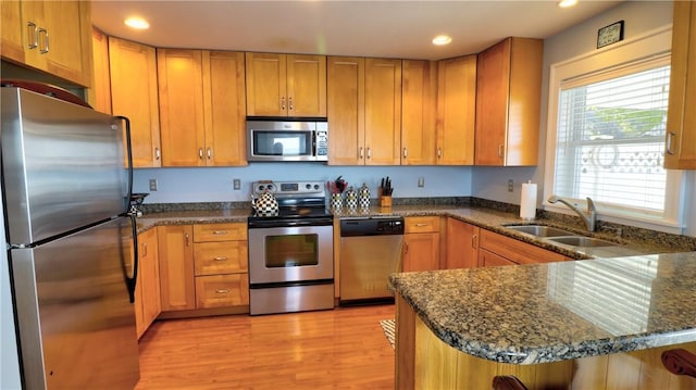 kitchen featuring appliances with stainless steel finishes, a sink, recessed lighting, a peninsula, and light wood-type flooring