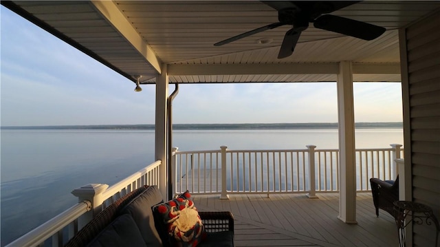 wooden deck with a water view and a ceiling fan