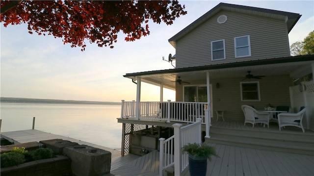 wooden deck with a ceiling fan, a water view, and outdoor dining space