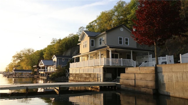 rear view of property with a water view, stairs, and fence