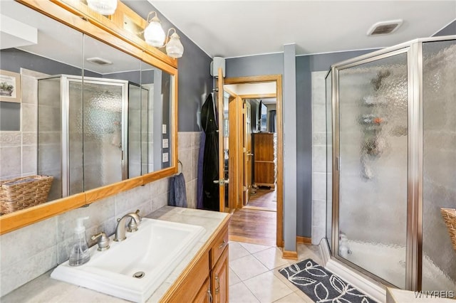 full bath featuring a shower stall, tile patterned flooring, tile walls, and vanity