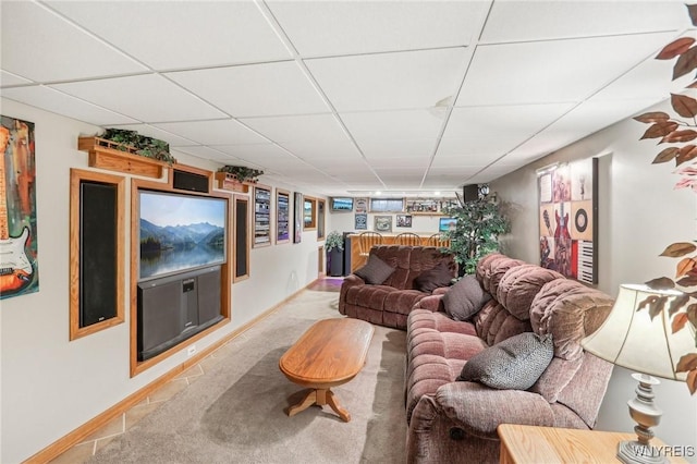 living area with a paneled ceiling, carpet flooring, and baseboards