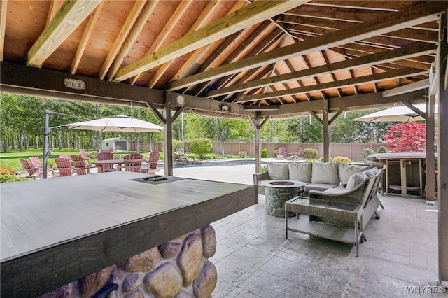 view of patio / terrace with a storage unit, an outdoor living space with a fire pit, a fenced backyard, and an outbuilding