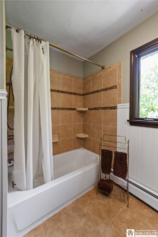 24 Castile Dr, Pomfret, NY 14063 - full bathroom featuring shower / bath combination with curtain, tile patterned floors, a wainscoted wall, and a baseboard heating unit