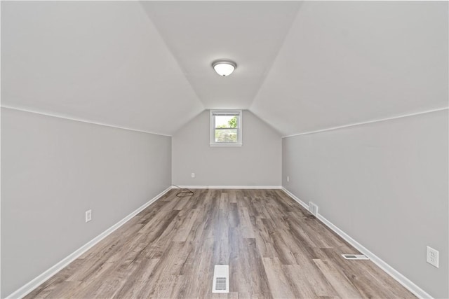 additional living space featuring wood finished floors, lofted ceiling, and baseboards