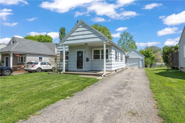 bungalow-style house with a garage, a front lawn, and an outbuilding