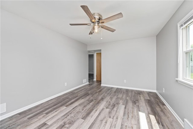 unfurnished room featuring healthy amount of natural light, wood finished floors, and baseboards
