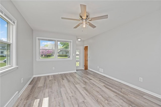 spare room featuring wood finished floors, a ceiling fan, and baseboards