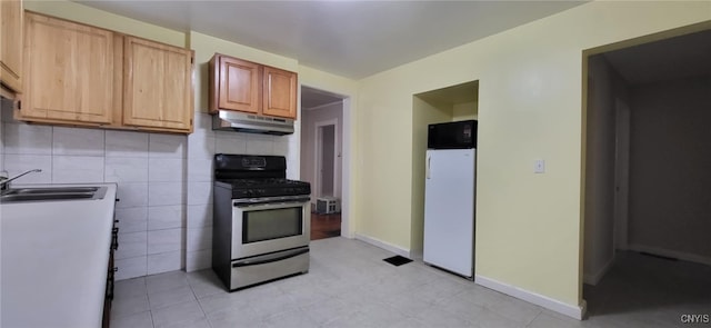 221 Grace St, Syracuse, NY 13204 - kitchen with stainless steel range with gas cooktop, a sink, under cabinet range hood, refrigerator, and decorative backsplash