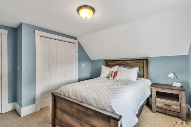 bedroom with light colored carpet, a closet, lofted ceiling, and baseboards
