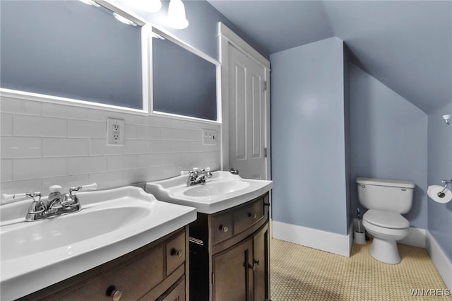 bathroom featuring two vanities, toilet, and baseboards