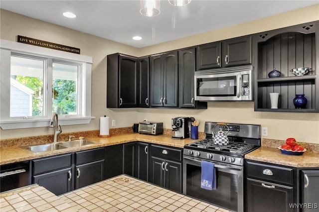 kitchen with appliances with stainless steel finishes, a sink, dark cabinetry, light countertops, and recessed lighting