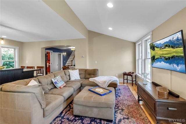 living area featuring arched walkways, wood finished floors, stairs, recessed lighting, and baseboards
