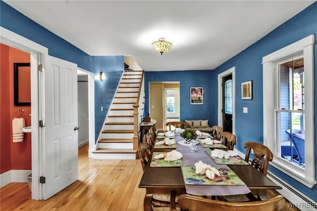 dining room featuring stairway, light wood-style floors, baseboard heating, and baseboards