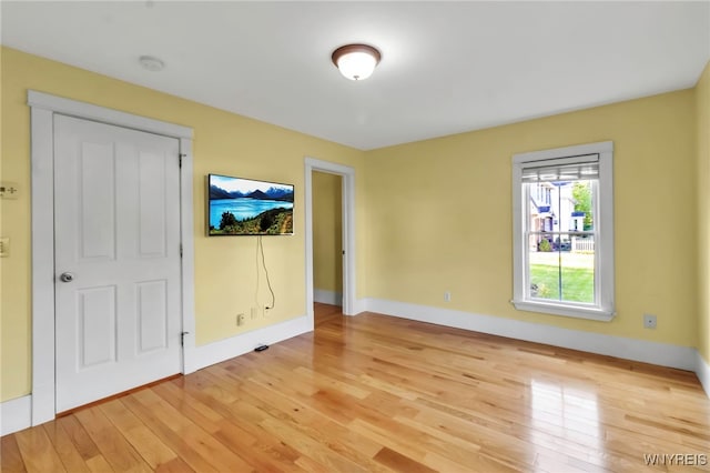 spare room featuring light wood-style floors, baseboards, and a smoke detector