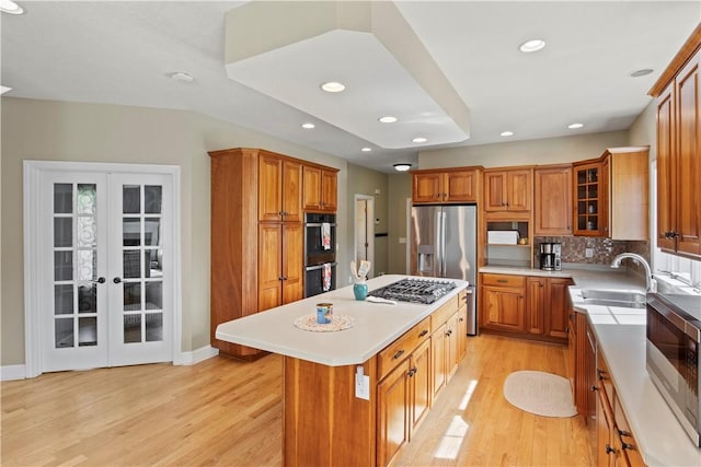 kitchen with a sink, appliances with stainless steel finishes, brown cabinets, and recessed lighting