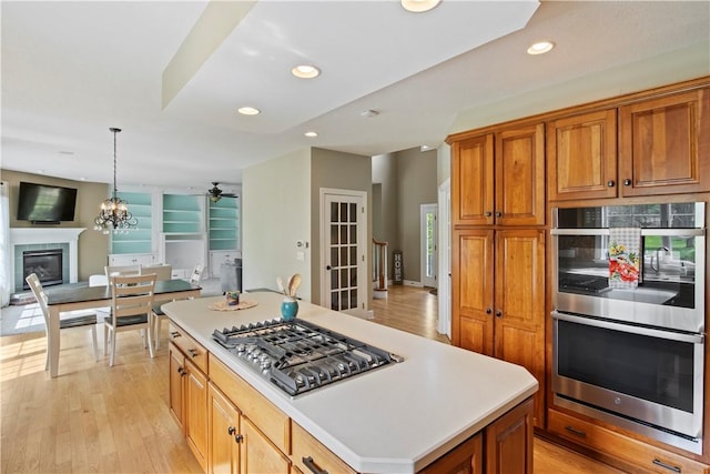 kitchen with appliances with stainless steel finishes, recessed lighting, light wood-style floors, brown cabinets, and open floor plan