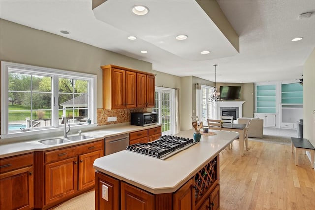 kitchen featuring stainless steel appliances, a sink, a fireplace, recessed lighting, and light countertops