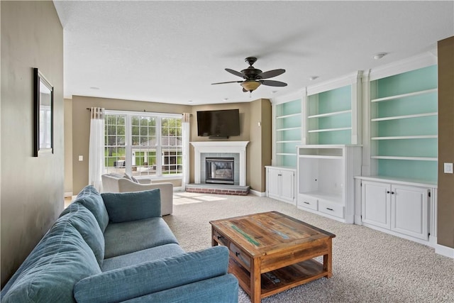 living area featuring a ceiling fan, a glass covered fireplace, carpet, and baseboards