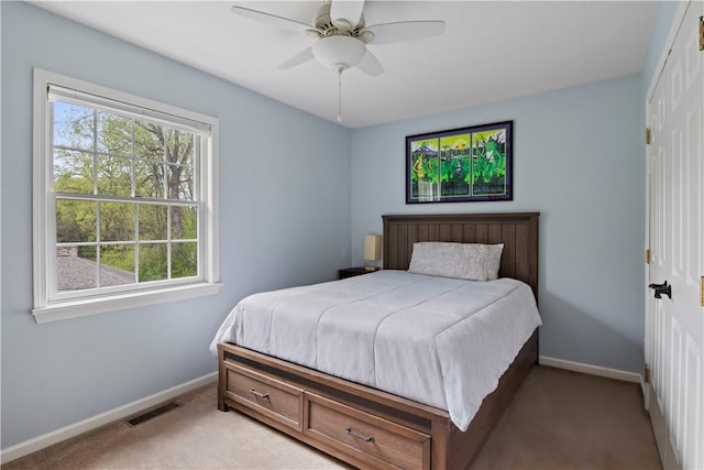 bedroom with baseboards, light colored carpet, a closet, and a ceiling fan